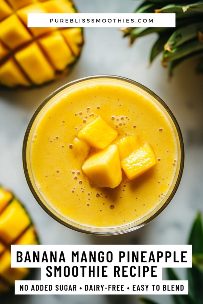 Top-down view of a banana mango pineapple smoothie in a glass, garnished with pineapple chunks. Surrounded by fresh mango and pineapple, with text overlay promoting a dairy-free, no added sugar tropical smoothie recipe from PureBliss Smoothies.