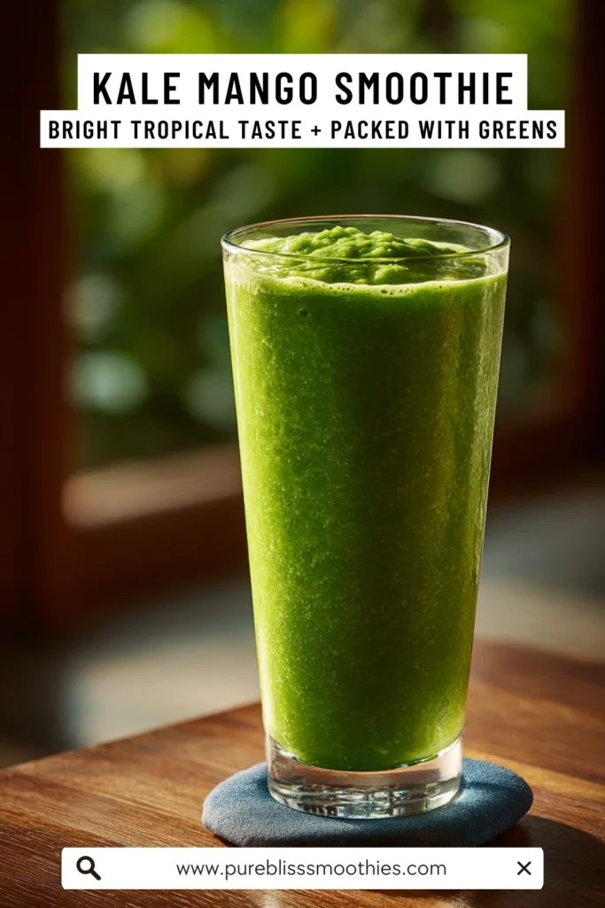 Tall glass of vibrant green kale mango smoothie on a wooden table, highlighted by natural light with a lush outdoor background.